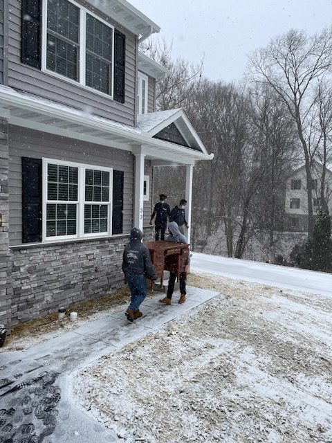 men moving items into a home with snow on the ground